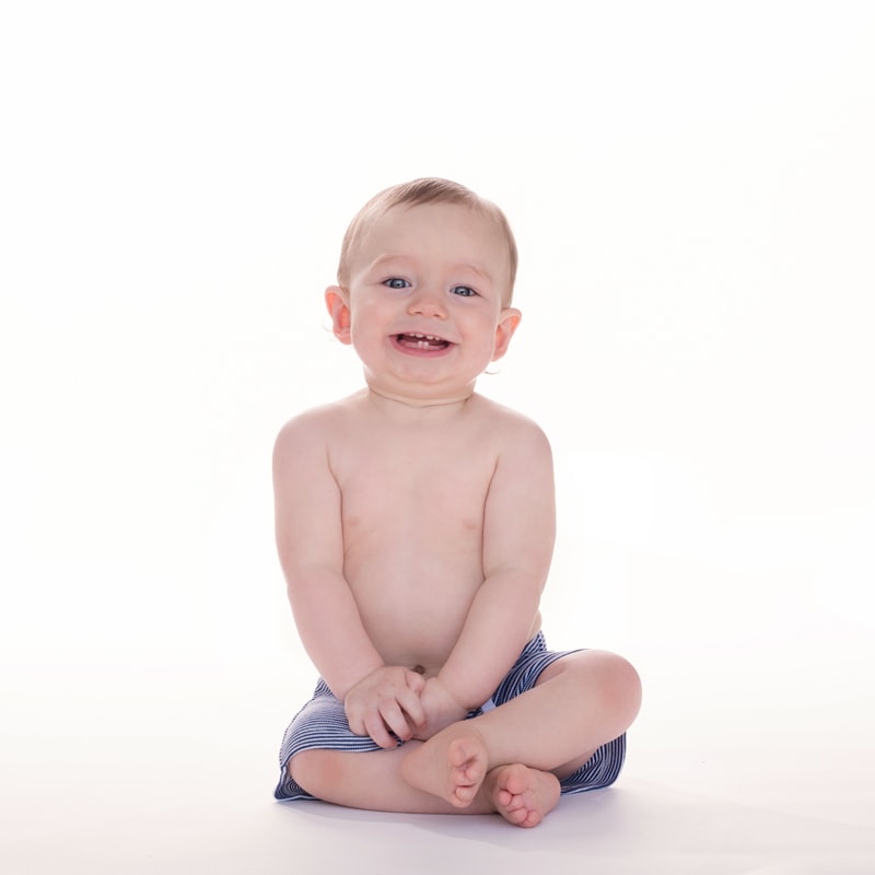 milestone photography, little boy sits up in studio smiling