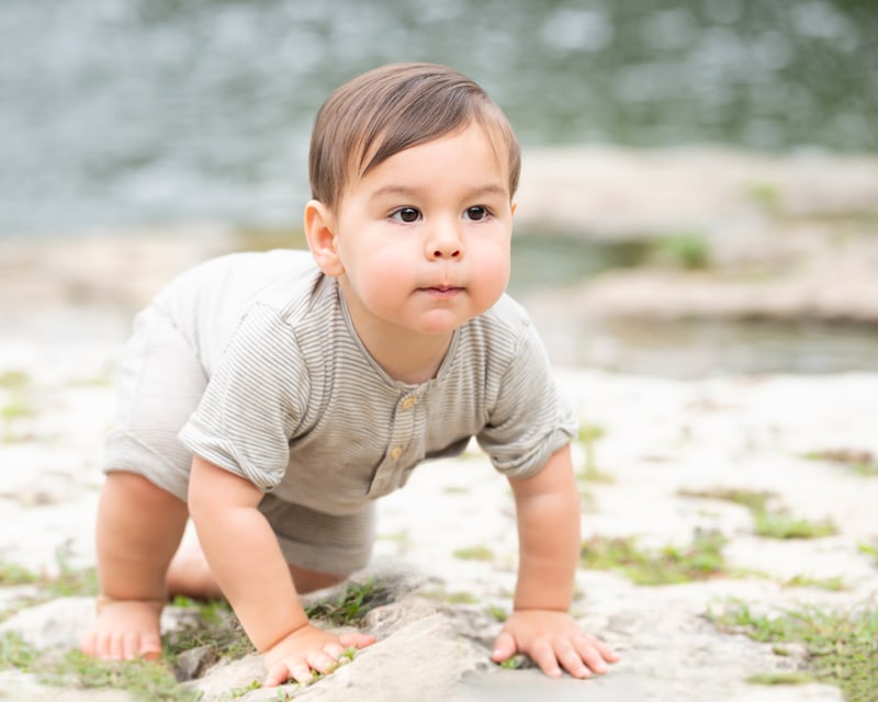 milestone photography, baby boy crawls in the sand near the lake shore