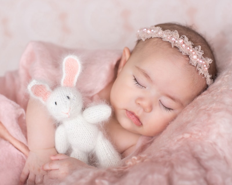 milestone photography, baby girl lays sleeping on fluffy blanket, a stuffed bunny lays on her
