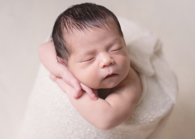 Newborn Photography, a little a bay lays sleeping with arms crossed and cozy