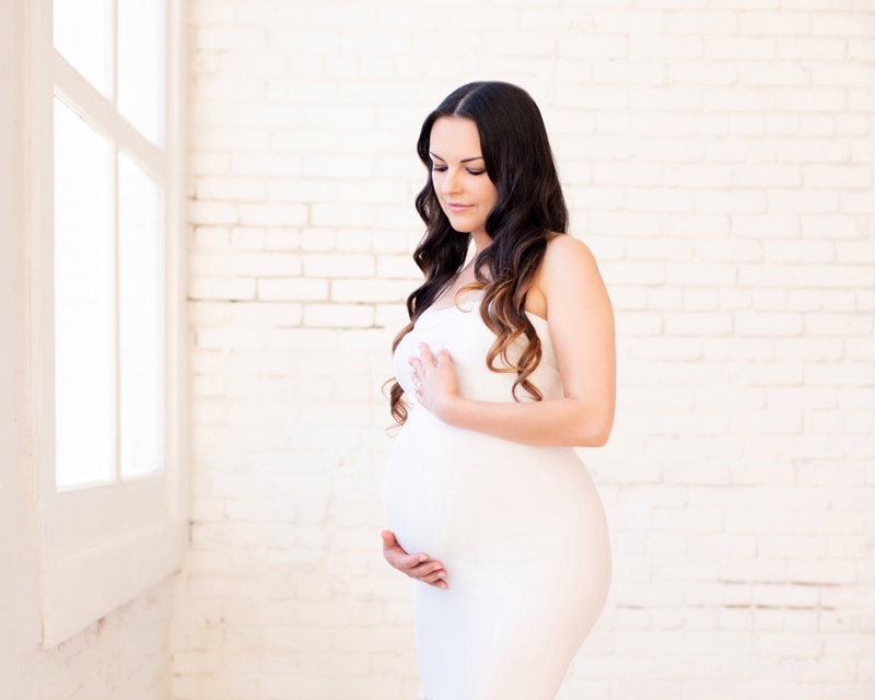 Maternity Photography, Expecting woman holds belly in anticipation of baby