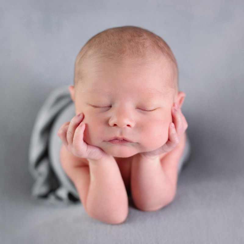Newborn Photography, a baby boy lays on his hands sleeping