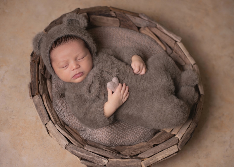 Newborn Photography,  a little baby wears a cozy bear outfit and lays sleeping in a basket