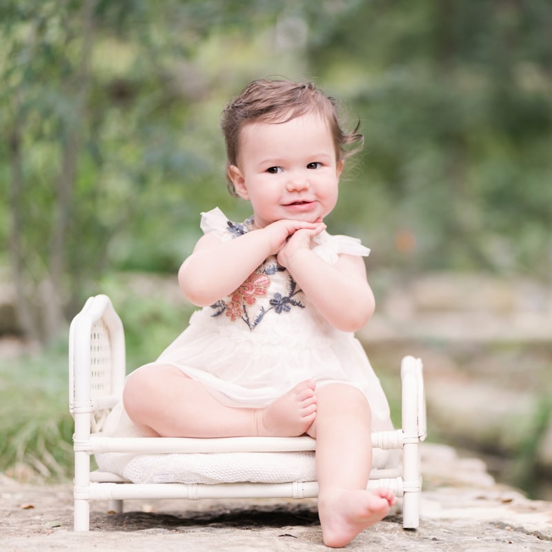 milestone photography, a baby sits on a tiny crib, she smiles