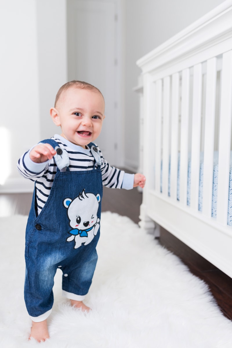 milestone photography, a baby in overalls begins to walk in the house