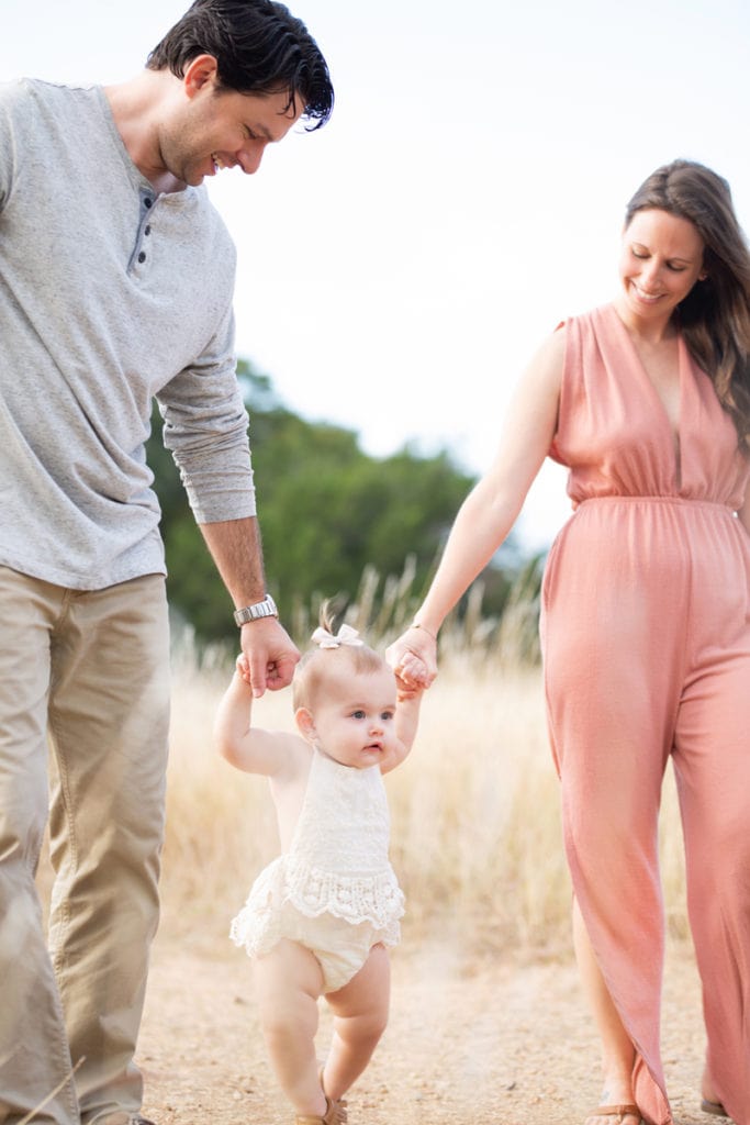Baby Photography, A mother and a father walk with their young baby daughter outdoors in a field