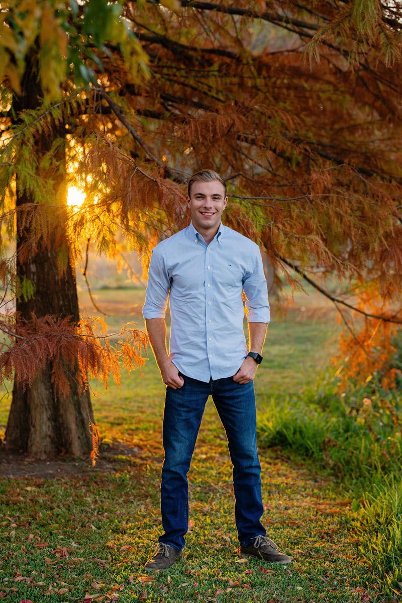 Senior Photographer, A high school man stands tall before autumn trees at golden hour