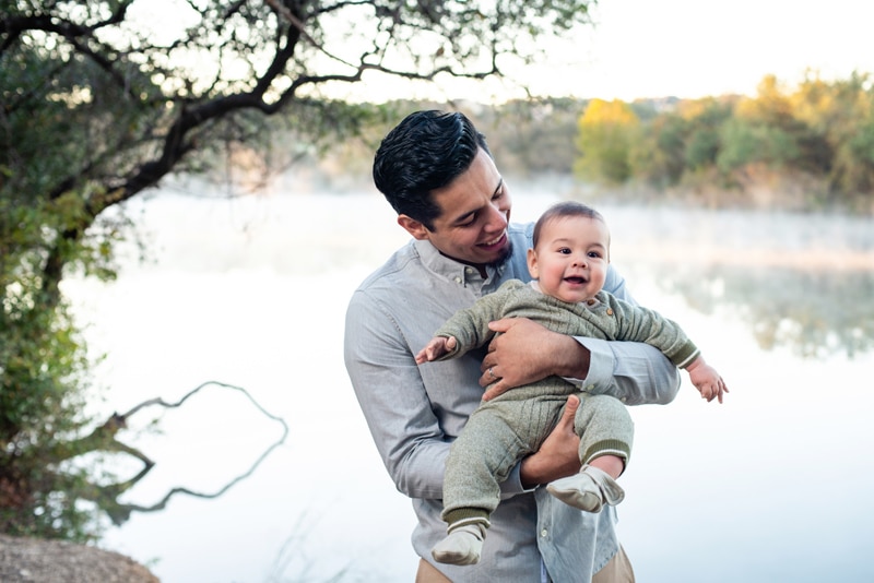 Family Photographer, Young dad holds his baby son near a lakeshore