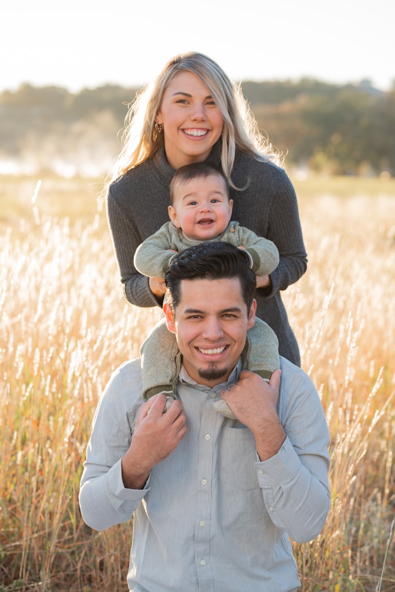 milestone photography, dad holds baby in shoulders as mom leans in from behind