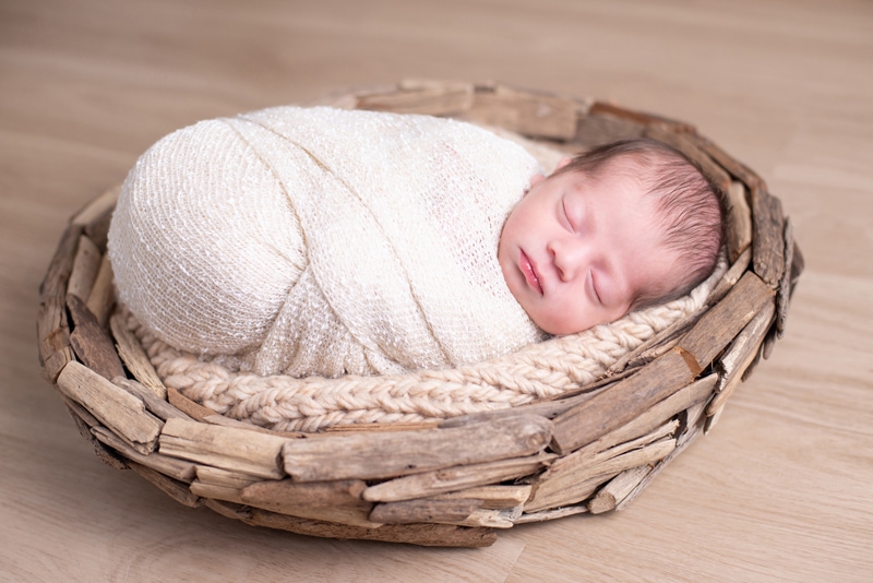 A baby lays sleeping cozily in a basket
