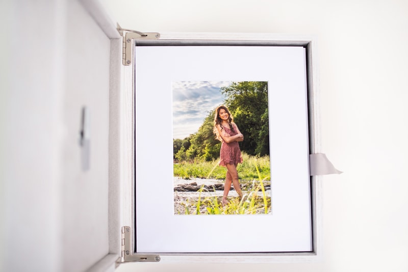 Senior Photography, A photo album lays open with a picture of a high school girl near a river bank