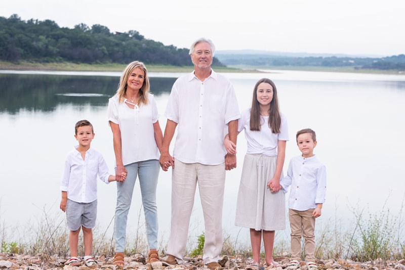 Family Photographer, grandparents hold hands with their three grandkids near the lake