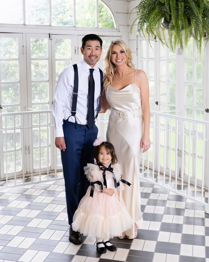 Family Photographer, young father and mother stand with their daughter, all dressed up