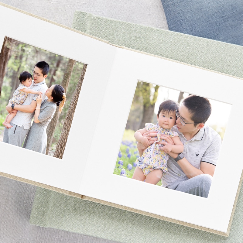 Newborn photographer, a photo album is folded open with pictures of families and their kids showing