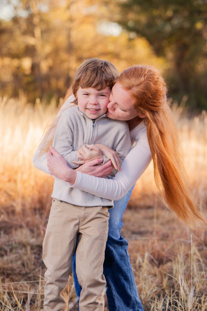 About the Photographer, Mother hugs her son in a dry grassy meadow