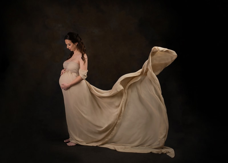 Maternity Photography, pregnant woman wearing an elegant dress with silk fabric toss