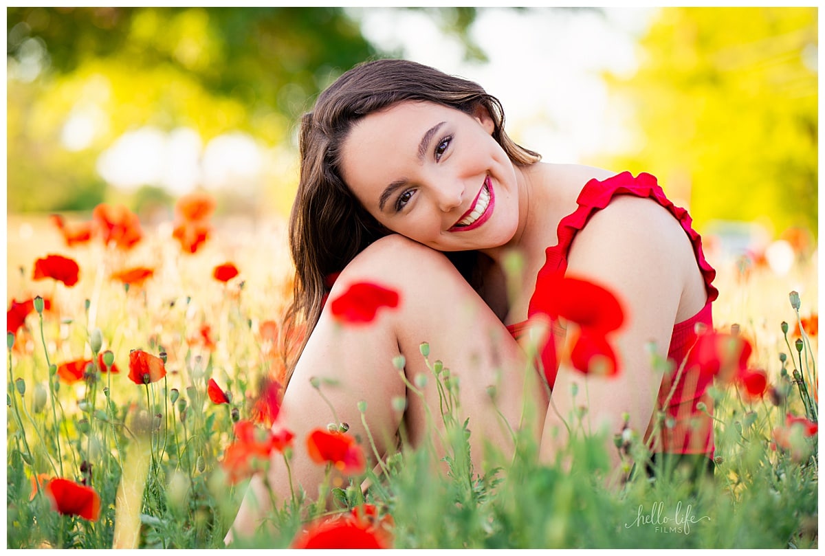 student rests head on knee in poppy field by Austin Senior Photographer